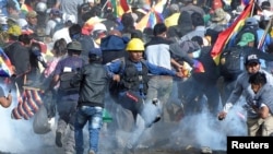 Coca growers, supporters of former President Evo Morales, run away from tear gas as one of them kicks a tears gas canister during clashes with riot police in Sacaba, in the outskirts of Cochabamba, Bolivia November 15, 2019. REUTERS/Danilo Balderrama