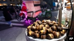 Chestnuts are displayed at a food vendor as a person dressed as Santa Claus offers rides, Dec. 12, 2024, in New York. 