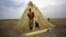 A woman from the Dinka tribe stands in front of her shelter near Bor, Jonglei state, in South Sudan, March 31, 2012.