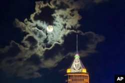 The full moon is shrouded in cloud above a Hong Kong skyscraper on the night of the Mid-Autumn Festival, a traditional holiday around Asia, Sept. 17, 2024.