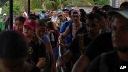 Migrantes que atravesaron el Tapón del Darién se alinean para inspecciones de sus pertenencias en Lajas Blancas, Panamá, el 26 de septiembre de 2024. Según el gobierno panameño, más de 196.000 venezolanos han cruzado esa zona boscosa de forma ilegal. (ARCHIVO: AP)