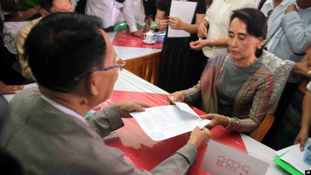 Myanmar opposition leader Aung San Suu Kyi, right, submits her documents for the upcoming general election at an election commission office on the outskirts of Yangon, Myanmar, July 29, 2015.