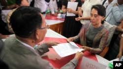 FILE - Myanmar opposition leader Aung San Suu Kyi, right, submits her documents for the upcoming general poll, election commission office, Yangon, Myanmar, July 29, 2015.