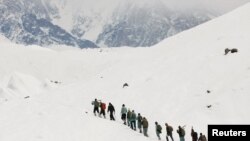 FILE - A group of Pakistani soldiers carry their guns uphill along the K2 base camp trek in the Karakoram mountain range in Pakistan, Sept. 8, 2014. 