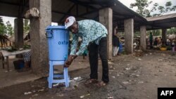 Un homme se lave les mains avec de l'eau provenant d'un distributeur contenant de l'eau mélangée à du désinfectant au Congo Air Market sur la route de l'aéroport à l'est de Mbandaka le 23 mai 2018.