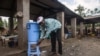 Un homme se lave les mains avec de l'eau provenant d'un distributeur contenant de l'eau mélangée à du désinfectant au Congo Air Market sur la route de l'aéroport à l'est de Mbandaka, le 23 mai 2018. (Photo: Junior D. KANNAH/AFP)