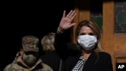 Bolivia's interim President Jeanine Anez, wearing a face mask to help curb the spread of the new coronavirus, waves during a procession Corpus Christi, in La Paz, Bolivia, June 11, 2020.