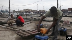 Nigerian refills a small generator on the rooftop of his store in Oshodi Market in Lagos in March, 2010. Despite rich oil resources, much of the nation’s economy depends on provide generators for power. 