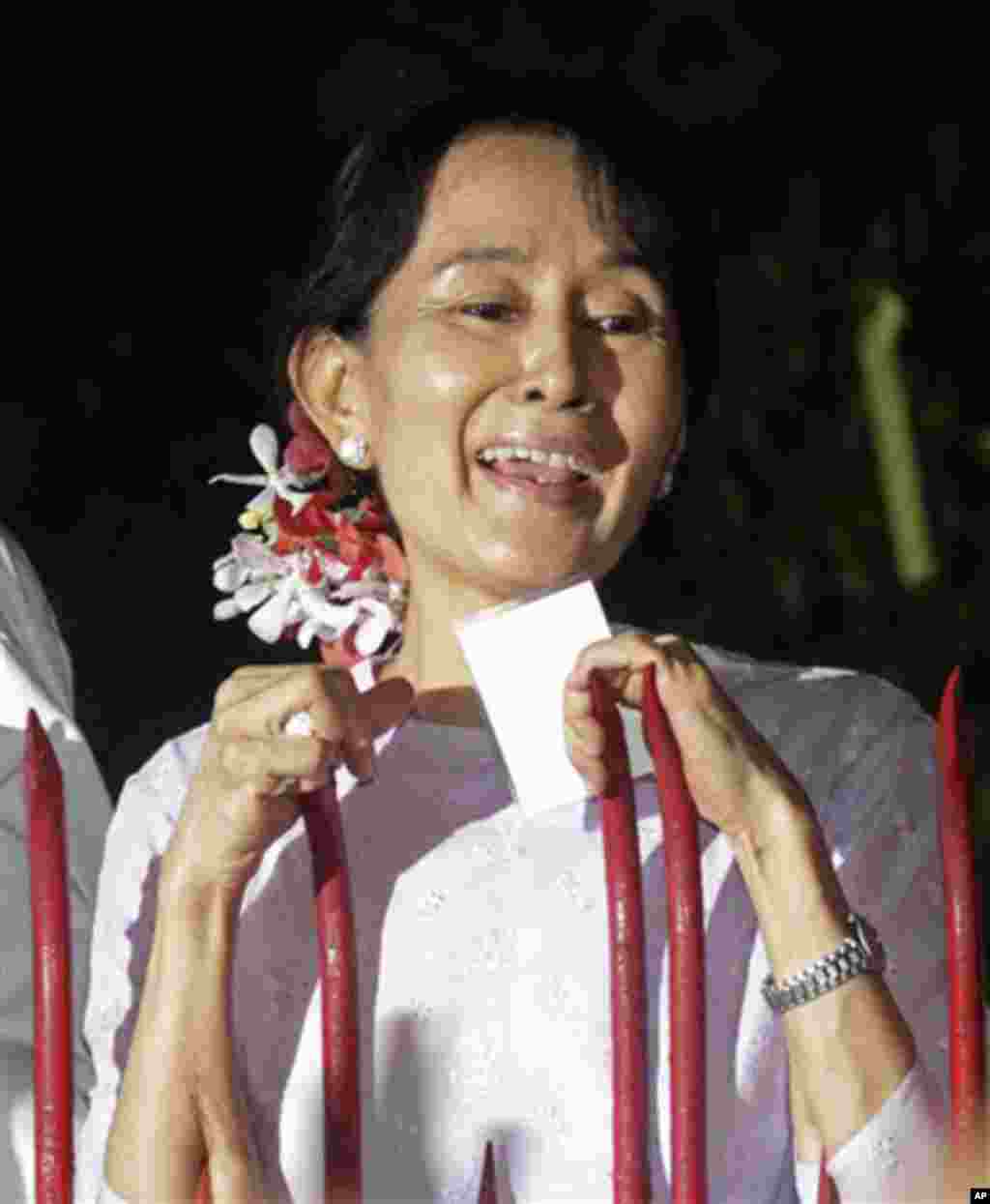 Burma's pro-democracy leader Aung San Suu Kyi talks to the supporters as she stands at the gate of her home in Rangoon, 13 Nov 2010.