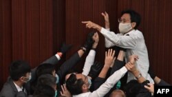 FILE - In this May 8, 2020, photo, pro-democracy lawmaker Eddie Chu Hoi-dick, top center, shouts at security trying to restrain him at a Legislative Council meeting in Hong Kong.