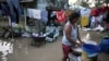 FILE - A woman stands beside laundry in a flooded village after Typhoon Yinxing, locally called Marce, blew past Buguey town, Cagayan province, northern Philippines, Nov. 8, 2024.