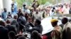 Zimbabwe President Emmerson Mnangagwa, center, leaves after paying his respects to the family of Morgan Tsvangirai, in Harare, Feb. 18, 2018. 