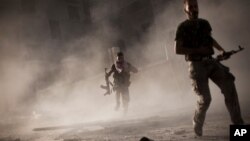 In this Friday, Sept 7, 2012 photo, Free Syrian Army fighters run after attacking a Syrian Army tank during fighting in the Izaa district in Aleppo, Syria.