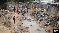 Somali people walk along a street after heavy rain storms hit the capital overnight, Mogadishu, June 8, 2018.