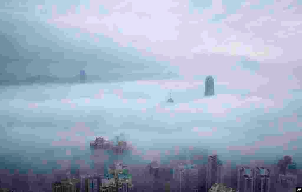 Two International Finance Centre tower, center right, and International Commerce Centre, top left, are seen over the clouds in Hong Kong.