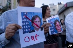 Warga Palestina membawa poster bergambar Menteri Luar Negeri AS Antony Blinken yang dicoret selama protes terhadap kunjungannya, di Kota Ramallah, Tepi Barat, Minggu, 5 November 2023. (Foto: AP)