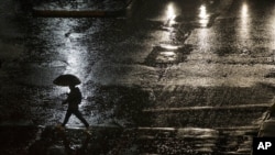 ARCHIVO - Un hombre camina bajo la lluvia en Santiago, Chile, el sábado 16 de abril de 2016.