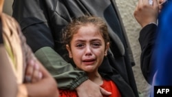 A girl cries as she and her relatives mourn the death of loved ones in Deir el-Balah on June 28, 2024, following Israeli bombardments in the Gaza Strip.