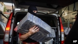 Seorang polisi membawa paket-paket berisi. kokaina di kantor jaksa urusan kejahatan terorganisasi di Bucharest, Romania, 1 Juli 2016. (Foto: Andreea Alexandru/AP Photo)