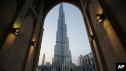 FILE - In this April 13, 2015, with the world tallest tower, Burj Khalifa, in the background, tourists and visitors watch and take photos of the Dubai Fountain in Dubai, United Arab Emirates.