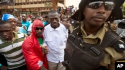 Ugandan opposition leader and presidential candidate Kizza Besigye, center, is detained by riot police after attempting to walk with his supporters along a street in downtown Kampala, Feb. 15, 2016.