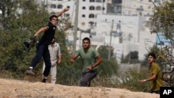 Muchachos israelíes lanzan piedras durante choques contra palestinos en las afueras del asentamiento judío de Kiryat Arba.