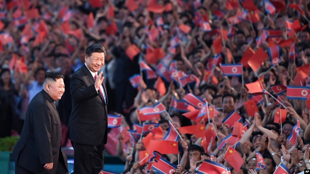 FILE - In this photo released by China's Xinhua News Agency, spectators wave Chinese and North Korean flags as North Korean leader Kim Jong Un, left, and visiting Chinese President Xi Jinping attend an event in Pyongyang, North Korea, on June 20, 2019.