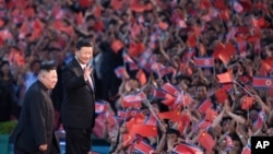 Penonton melambaikan bendera China dan Korea Utara saat Kim Jong Un dan Xi Jinping bertemu di Pyongyang, Korea Utara, 20 Juni 2019. (Yan Yan/Xinhua via AP)