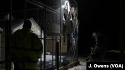 FILE - A volunteer and security guard stand outside one of Lesvos’ temporary camps.