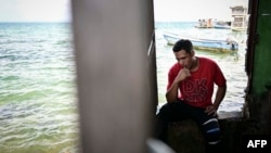 A Venezuelan migrant uses his phone as he waits to be transferred to Colombia by sea on the island of Carti, Guna Yala territory in Panama, Feb. 24, 2025.