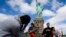 Tourists pose for photographs in front of the Statue of Liberty in New York Harbor in New York. The Statue of Liberty reopened to the public after the state of New York agreed to shoulder the costs of running the site during the partial federal government