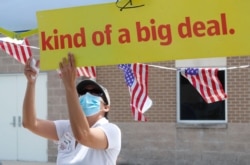 FILE - Census worker Marisela Gonzales adjusts a sign at a U.S. Census walk-up counting sight set up for Hunt County in Greenville, Texas, July 31, 2020.