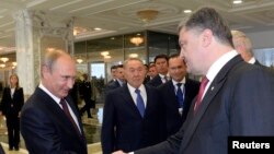 Presiden Rusia Vladimir Putin (kiri) berjabat tangan dengan Presiden Ukraina Petro Poroshenko dalam pertemuan di Minsk (26/8). (Reuters/Sergei Bondarenko)