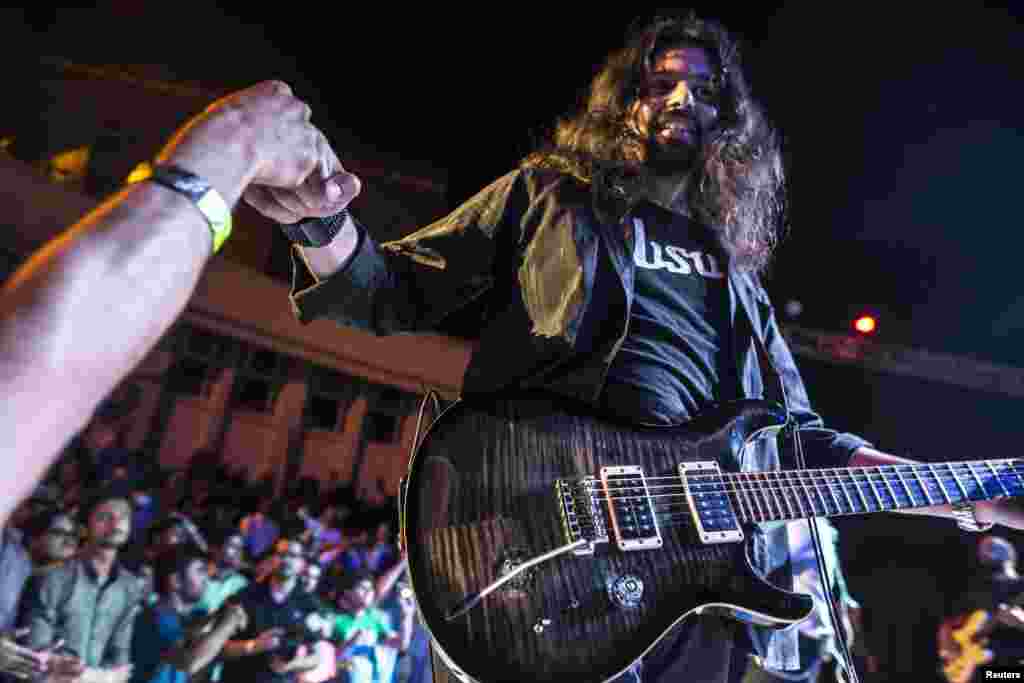 راک بینڈ قیاس کے گٹارسٹ خرم وقار لوگوں کے سامنے اپنے فن کا مظاہرہ کر رہے ہیں۔