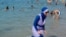 FILE - A woman wearing a burkini walks in the water on a beach in Marseille, France, Aug. 27, 2016. 