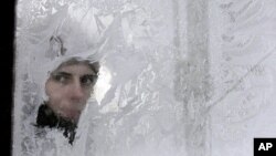 A woman looks through an icy window in a bus in Ukraine's capital, Kyiv, February 3, 2012.
