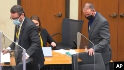 In this image from video, defense attorney Eric Nelson, left, and defendant Derek Chauvin take their seats ahead of jury selection, March 10, 2021, at the Hennepin County Courthouse in Minneapolis.