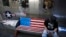 FILE - A man browses his smartphone on a bench decorated with a U.S. flag, outside a fashion boutique selling U.S. brand clothing at a shopping mall in Beijing, China, May 13, 2019.
