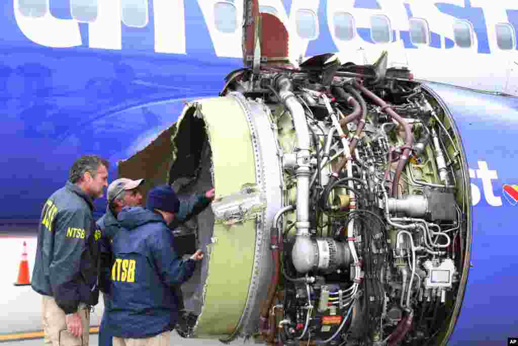 National Transportation Safety Board investigators examine damage to the engine of the Southwest Airlines plane that made an emergency landing at Philadelphia International Airport in Philadelphia, April 17, 2018. An &quot;uncontained&quot; engine failure sent debris flying like shrapnel into the plane and it broke a window. Passengers desperately saved a woman from getting sucked out. She later died and seven others were injured.