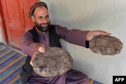 FILE - 37-year-old farmer Mohaiyudeen displays packages of opium after harvesting it from his poppy fields in the Surkh-Rod district of Nangarhar province, Afghanistan, June 28, 2020.