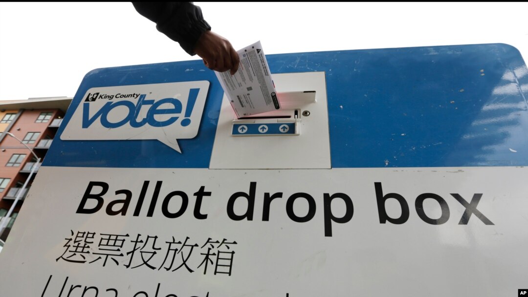 FILE - Voters drop off ballots in the Washington state primary, in Seattle, March 10, 2020.