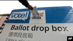 FILE - Voters drop off ballots in the Washington state primary, in Seattle, March 10, 2020.
