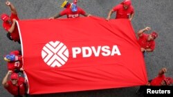 Trabajadores de PDVSA, la petrolera estatal venezolana levantan una bandera con el logo de la corporación durante una protesta contra el imperialismo en Caracas. Foto de Archivo. Marzo 18 de 2015.