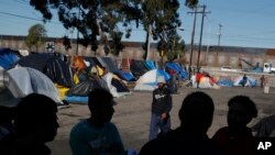 Men discuss rumors of other migrants who successfully snuck into the U.S. in a tent camp outside the closed Benito Juarez sports complex, in Tijuana, Mexico, Friday, Dec. 7, 2018. 