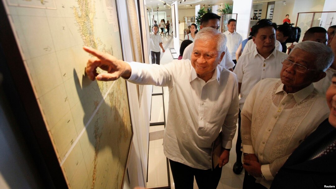 Philippines' Foreign Secretary Albert Del Rosario, points to a ancient map on display while Defense Secretary Voltaire Gazmin (R) looks on during the opening, at a Catholic university in Manila, Sept. 11, 2014. 