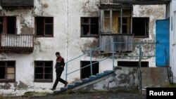 FILE - A laborer walks downstairs as he leaves a gym of a local school in Zapolyarny settlement outside the far northern city of Vorkuta, Russia, Sept. 17, 2018.