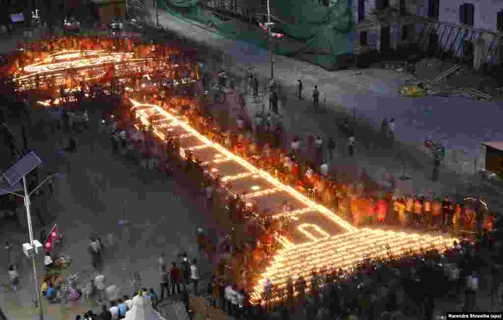 Nepalese gather to attend a candlelight vigil over an art of Dharhara Tower and Kasthamandap temple to mark the one year anniversary of devastating earthquake in Kathmandu, Nepal.