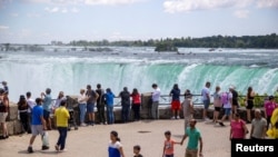 FILE - Tourists take photos in front of Niagara Falls in Niagara Falls, Ontario, Canada June 28, 2022. 