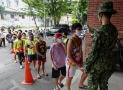 Men who were arrested for violating quarantine health protocols have their temperatures checked at the Amoranto Sports Complex in Manila, Philippines, July 8, 2020.