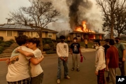 Residents embrace outside of a burning property as the Eaton Fire swept through Jan. 8, 2025 in Altadena, California.